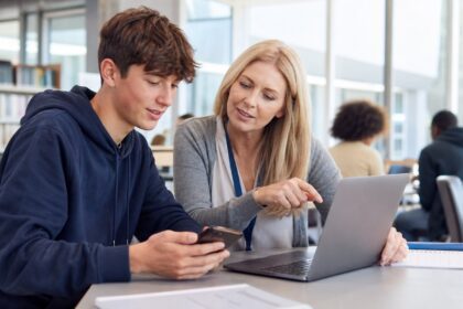 Student and teacher adviser reviewing digital exam records on secure devices